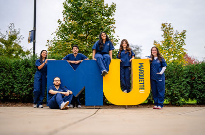 Students sitting on MU letter statue. Links to Beneficiary Designations